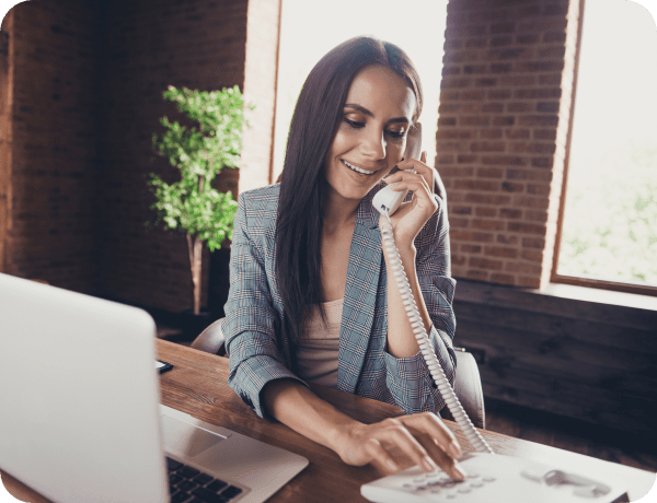 A woman sitting at her desk making a phone call using Internet phone service