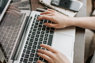 A pair of hands typing on a laptop