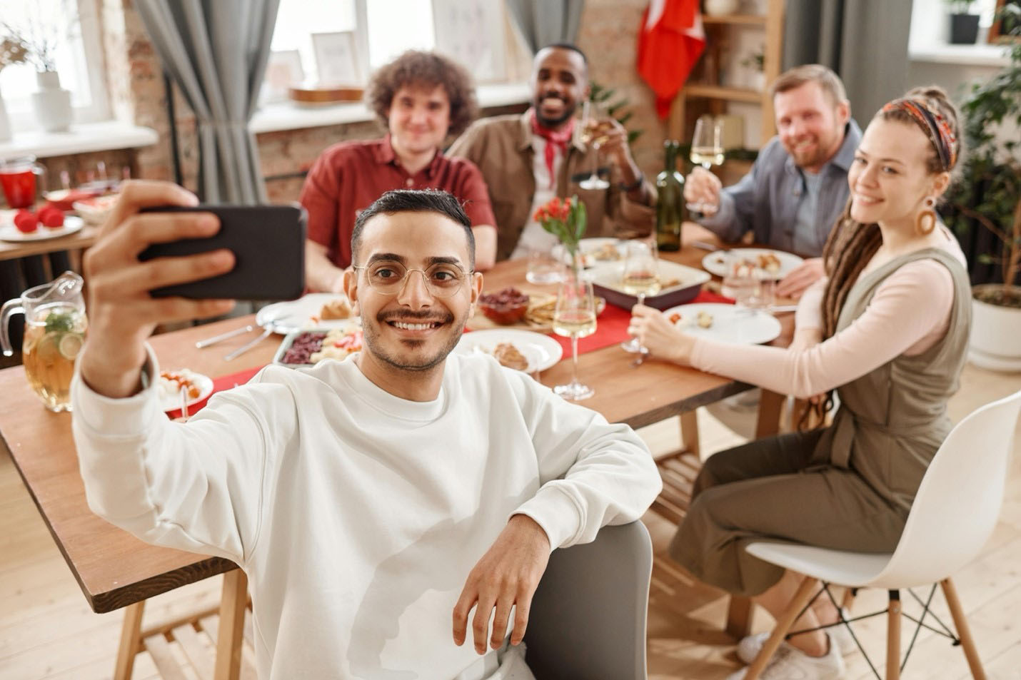 A dinner party using a smart phone to take a group selfie around the table