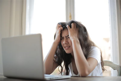 Woman using a laptop, visibly frustrated over a lost Internet connection.