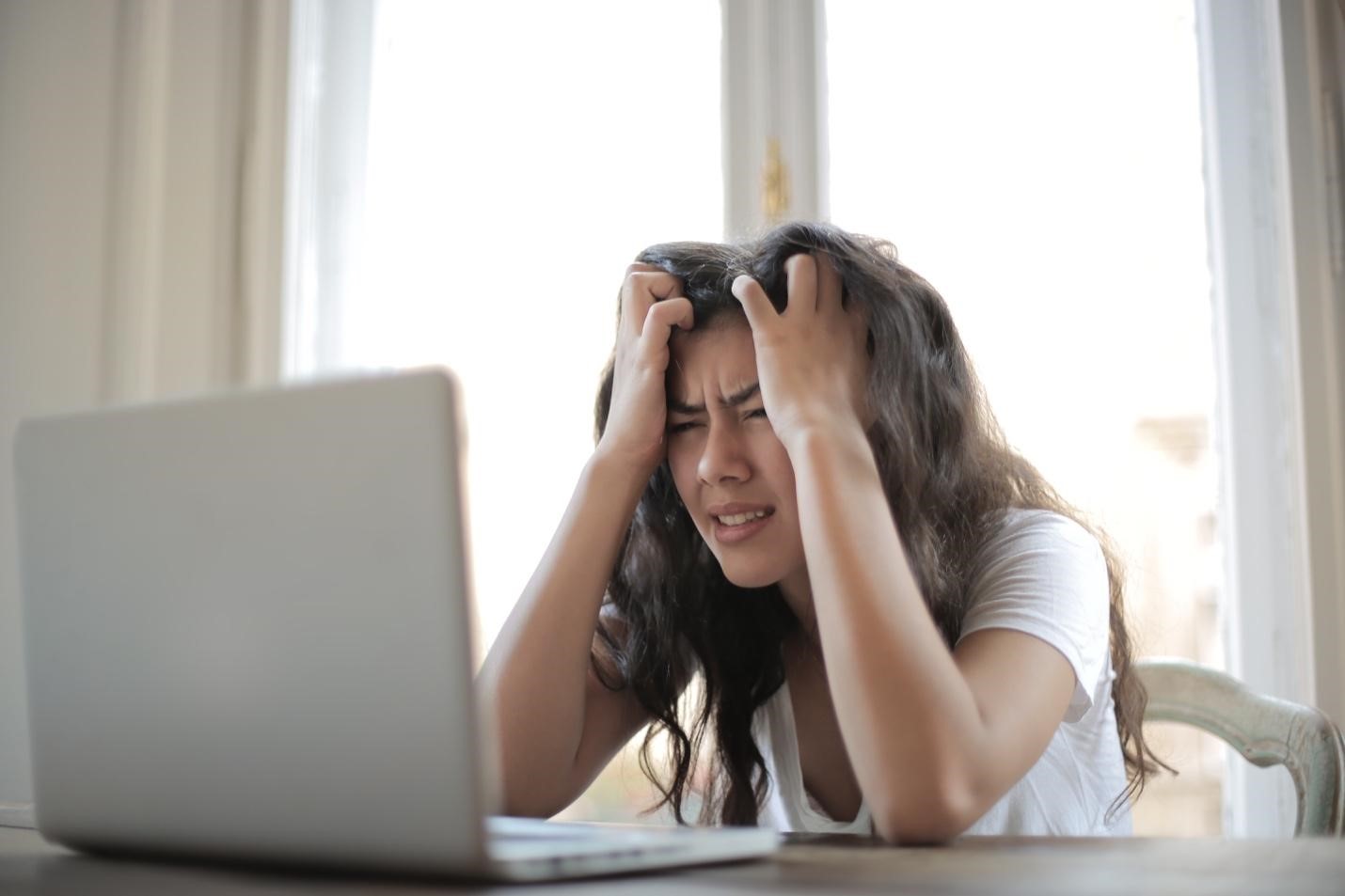 Woman using a laptop, visibly frustrated over a lost Internet connection.