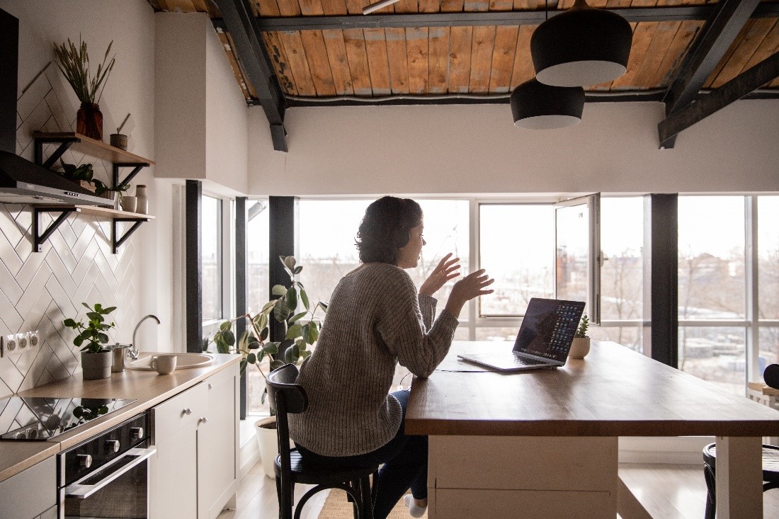 A woman using fiber optic internet for video conferencing in her kitchen