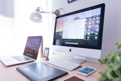 An office set up with a desktop, laptop, and tablet