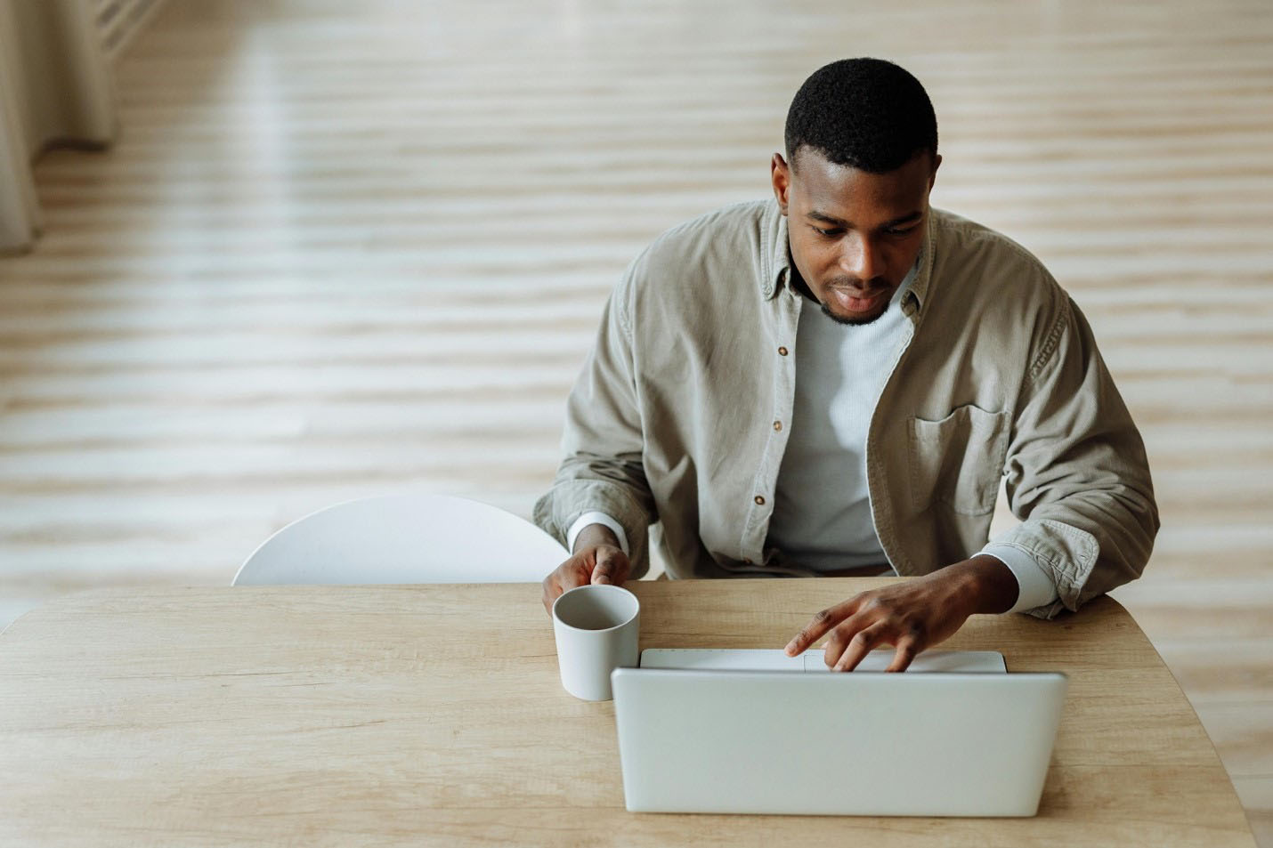 Man using a laptop computer at a table inside a home