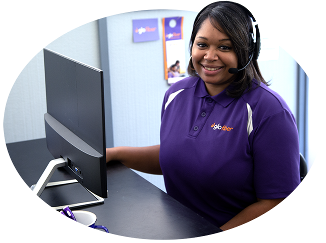 A smiling Glo Fiber technician wearing a headset takes calls and offers exemplary customer service for fiber optic internet customers