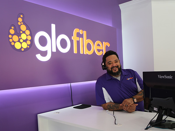 A Glo Fiber Employee smiling while sitting at a Glo Fiber customer service desk