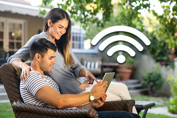A smiling couple browsing on their tablet using Glo Fiber Outdoor WiFi