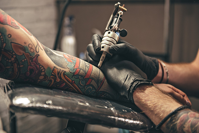 Close up of the hands of a tattoo artist applying a tattoo to someone's arm